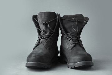 New stylish black suede leather tracking boots on grey background.  Winter footwear concept. Copy space for a free text