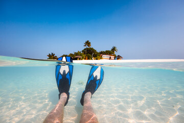 Split image, fins underwater and island in the Maldives
