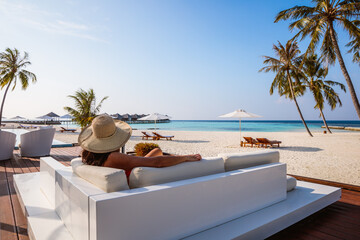 Woman relaxing on a sofa at the beach on a tropical island, Maldives