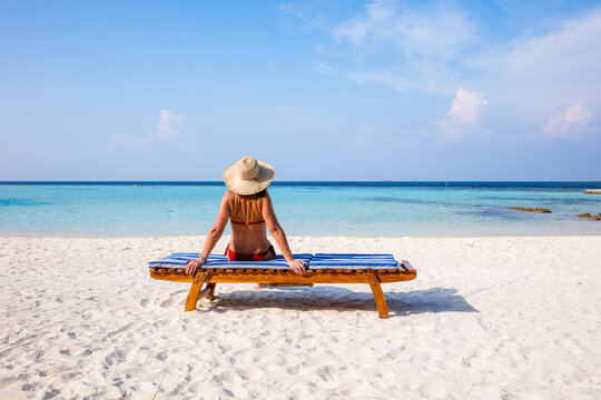 Woman sitting on lounge chair on the beach, Maldives