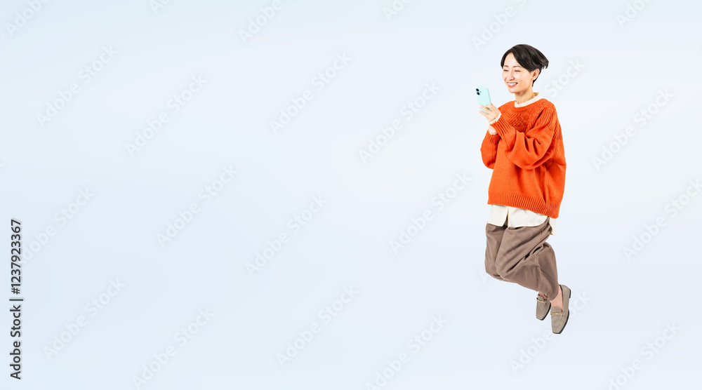 Poster スマホを見ながらジャンプするおしゃれなミドル女性の全身写真（切り抜き背景透過pngも販売しております。作成者リンクから「png」で検索してください）