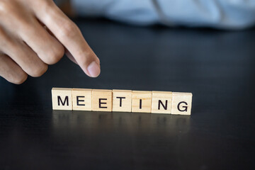 MEETING concept. Business man hand holding wooden cube words MEETING on a wood block