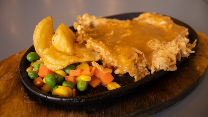 Crispy Chicken Steak with Glossy Sauce and Vegetables on Hotplate – Culinary Promotion