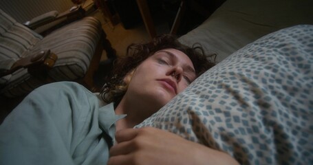 A woman is crying and hugging a pillow lying in bed at home. The mascara is smeared under the eyes
