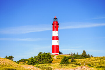 View of the dunes on the North Frisian island of Amrum. Landscape in the north. Nature on the North Sea island with a lighthouse.
