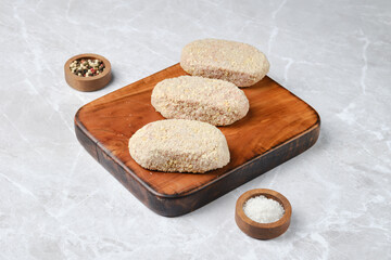 Freshly prepared breaded cutlets on a wooden cutting board in a clean kitchen setting
