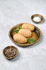Chicken semi-finished cutlets on a wooden plate with spices and herbs