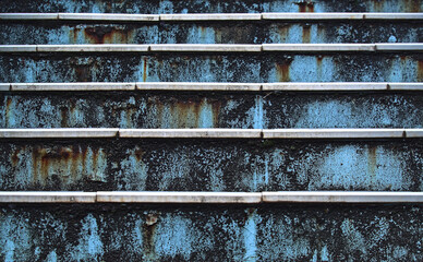 Close-up head-on view of part of a rusty metal blue-painted outdoor staircase