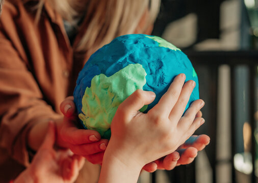 Mother and son holding sculpted clay Earth at home