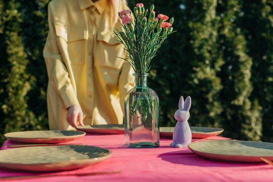Woman setting table for Easter lunch in back yard on sunny day