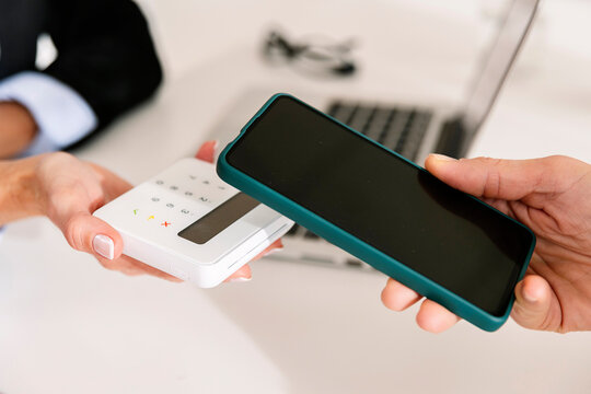 Hand of woman paying through smart phone on credit card reader