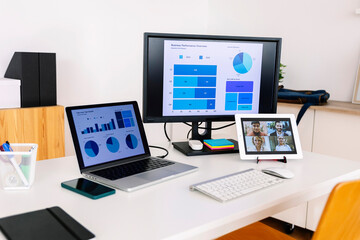 Business people discussing over video call with graphs and charts on computers screens at desk