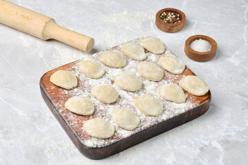 Freshly made dough dumplings prepared for cooking with a rolling pin nearby
