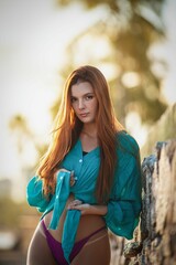 Woman in turquoise shirt by stone wall.