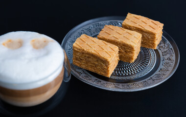 Coffee with layers, in a transparent mug and wafers on a transparent plate