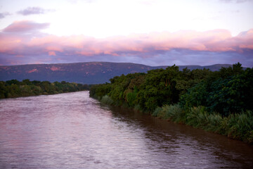Forest, lake and water outdoor at sunset for travel, holiday or vacation location with sky. Woods, river and mountain with landscape environment, clouds and ecosystem with trees for tourism in Chile