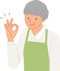 笑顔で手でOKポーズをするエプロンのシニア女性