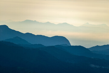 Soft sunlight breaks over the misty hills of Kodaikanal, highlighting the layered mountain ranges.