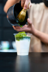 Man making matcha latte green tea beverage with traditional accessories closeup