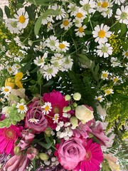 Floral bouquet with a mix of pink roses, gerbera daisies, white chamomile flowers, and lush greenery