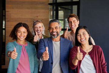 Portrait of successful and smiling business team with thumbs up