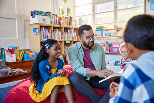 Teacher reading a fairy tale to pupil at school library