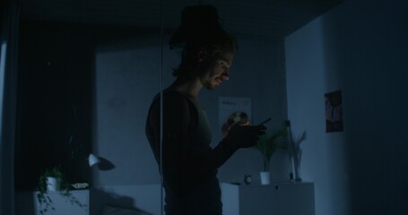 A man uses a mobile phone while walking around the bedroom at night. His wife is sleeping in bed....