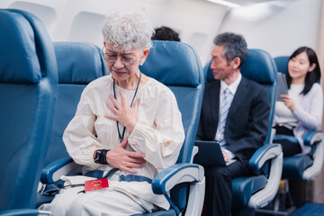 Obraz premium 飛行機の機内で体調不良に苦しむ高齢の女性