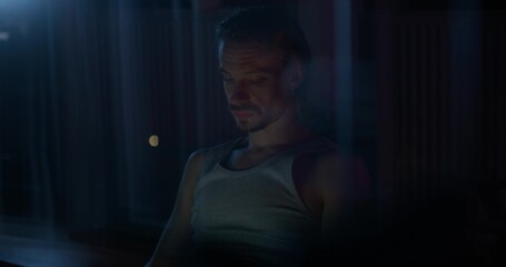 A man uses a laptop while sitting on the couch at night.