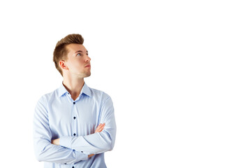 A young man in a striped blue shirt with arms crossed looks upward thoughtfully, isolated on a white background. Concept of thinking or confidence