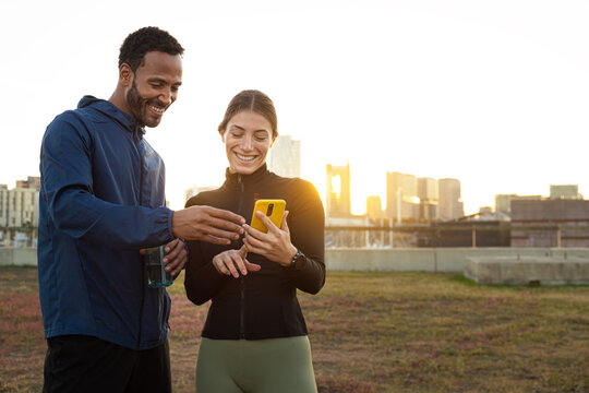 Runners using smartphone app after workout in city at sunset