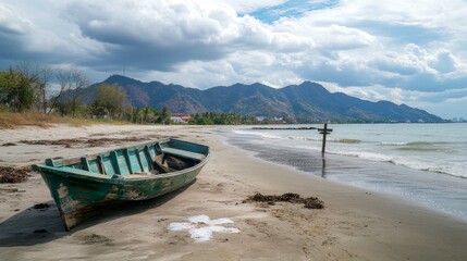 Obraz premium the beach with a boat and a cross on the sand, and mountains in the background.