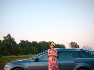 Traveler woman in red ethnic dress and hat drives car through scenic countryside of Croatia in...