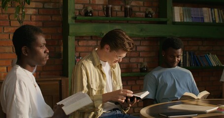 Men read Bibles and discuss what they have read while sitting at a table indoors. Daylight