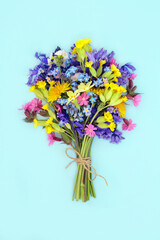 Spring wildflower bouquet  for Beltane May Day festival or floral bouquet for birthday, Mothers Day gift. Decoration of woodland and meadow flowers. On pastel blue.