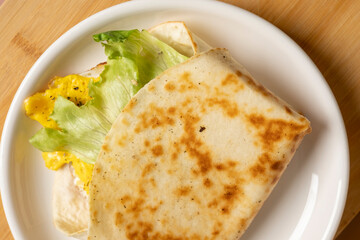 Sandwich in flatbread with lettuce and egg on plate on table close-up top view