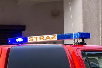 Polish state fire brigade. a heavy fire extinguishing vehicle and a command vehicle standing with a signal and blue lights against the background of a building. rescue and firefighting operation.