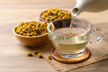 Chrysanthemum tea in teapot pouring into cup glass, Healthy herbal drink