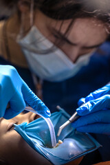 The dentist treats the child's tooth using a rubber dam. Close-up of tooth treatment.