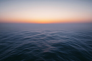 Obraz premium Sunset over calm ocean waters creates a serene atmosphere with vibrant colors on the horizon