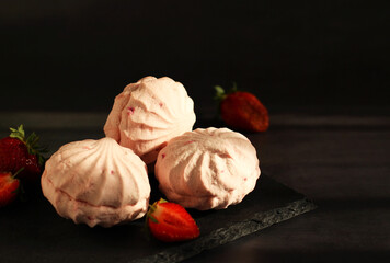 Dessert marshmallow pink with strawberries close-up on a black background