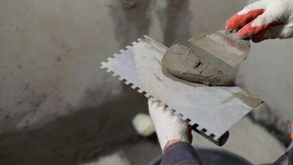 Construction worker applying cement on trowel with spatula