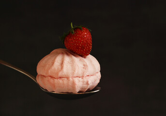 Dessert berry pink marshmallow with strawberries cut on a spoon on a dark background