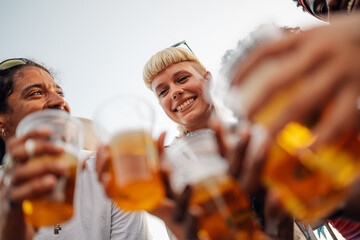 Happy friends toasting with beer glasses at music festival