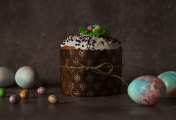 Easter cupcake with white icing and colorful eggs on dark background