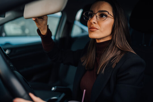 Businesswoman adjusting sun visor while driving modern car