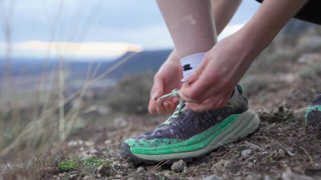 Close-up of a hiker tying shoelaces on a trail running shoe before a mountain trek
