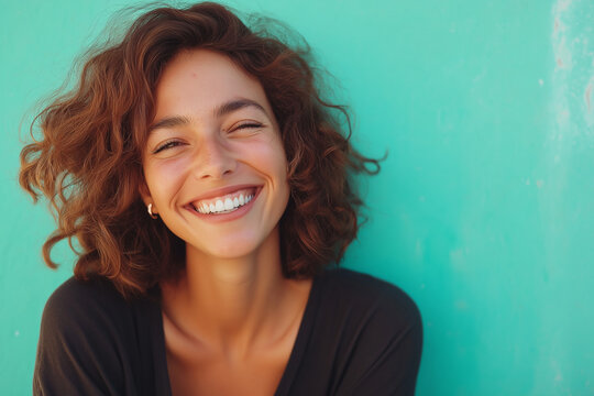 A woman with curly hair is smiling and has her teeth showing