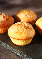 Dessert muffins with sugar crust on a black stand on a dark background