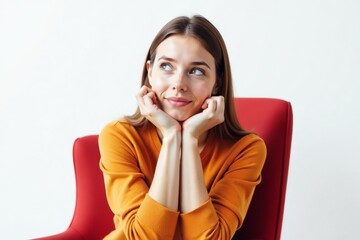 A woman sitting in a red chair, deep in thought, reflecting on ideas or decisions in a modern setting.